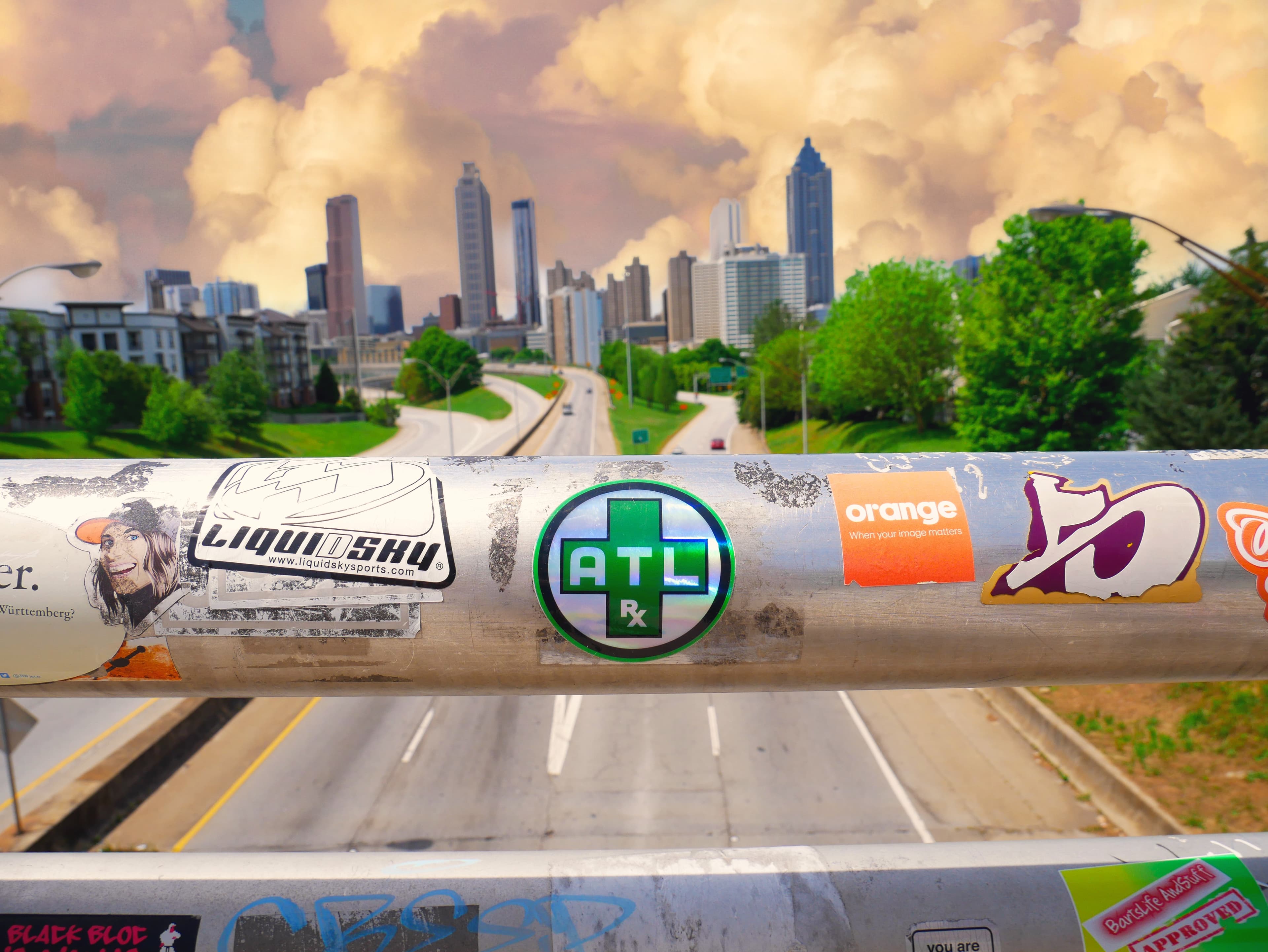 An ATLRx sticker on a bridge railing with the Atlanta skyline behind it